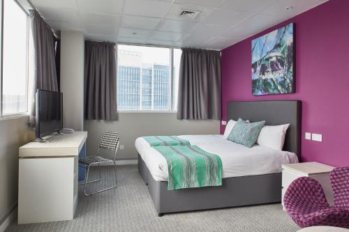 a bedroom with a bed and a purple wall at Cardiff Bute Terrace Hotel By Belvilla in Cardiff