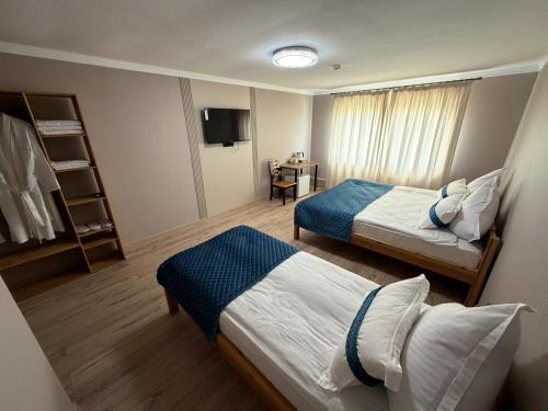 a hotel room with two beds and a tv at DEMAL Mountain Resort in Alamedin