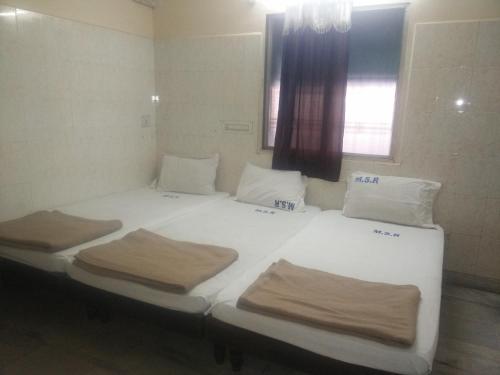 two twin beds in a room with a window at MSR Lodge in Tirupati