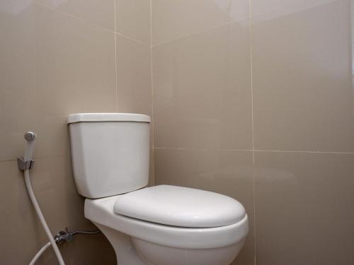 a white toilet in a bathroom with a hose at RedDoorz Plus @ Karangploso in Karangploso