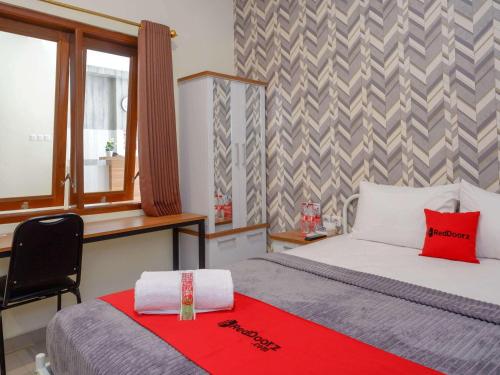 a bedroom with a bed and a desk and a window at RedDoorz Plus @ Karangploso in Karangploso