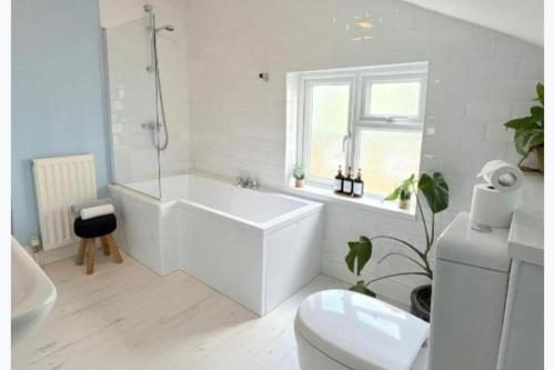 a white bathroom with a tub and a toilet at Walton Beach 1-Bed Cottage Sleeps 2 with Parking in Walton-on-the-Naze