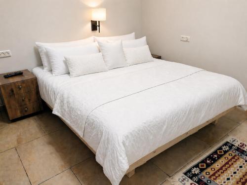a large white bed with white sheets and pillows at Elinor's Secret Suite in Sulam Tsor