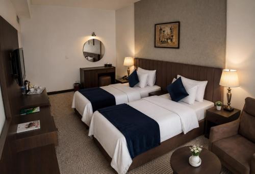 a hotel room with two beds and a couch at فندق بغداد Baghdad International Hotel in Baghdād