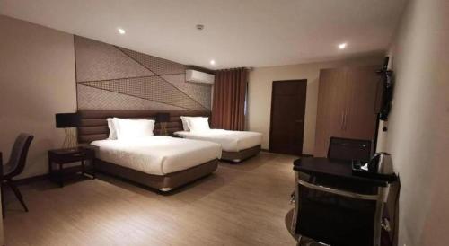 a hotel room with two beds and a flat screen tv at Maxx Hotel Ortigas in Manila