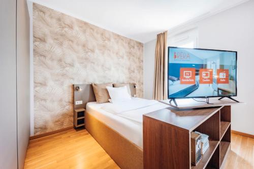 a hotel room with a bed and a flat screen tv at Brera Serviced Apartments Ulm in Ulm