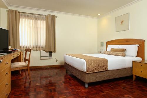 a hotel room with a bed and a television at City Garden Suites Manila in Manila