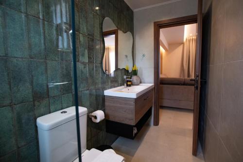a bathroom with a sink and a toilet and a mirror at Matsi Suites in Faliraki