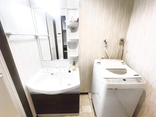 a white bathroom with a sink and a mirror at コンドミニオ久貝 in Miyako-jima