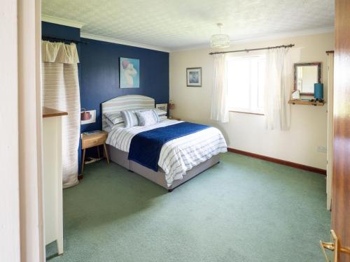 a bedroom with a bed and a blue wall at Idyllic, Luxurious Seaside Flat for 4. in Borth
