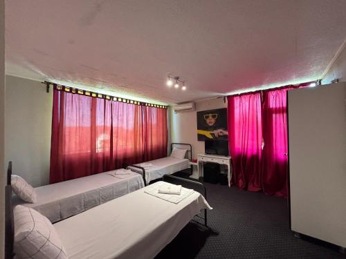 a room with two beds and pink curtains at Pensiunea Casa Copou in Iaşi