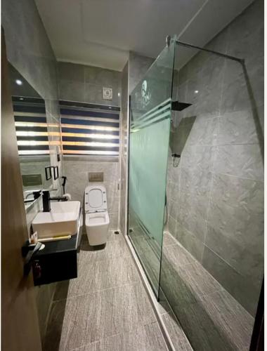a bathroom with a shower and a toilet and a sink at Rivona Hotels & Suites in Uyo