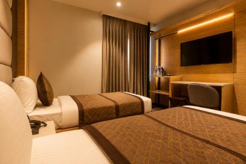 a hotel room with two beds and a television at Hotel Bricks, Karol Bagh, New Delhi in New Delhi