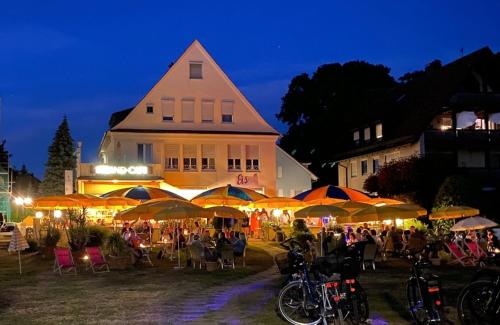 a group of people sitting under umbrellas in front of a building at Hotel Strand-Café mit Gästehaus Charlotte in Langenargen