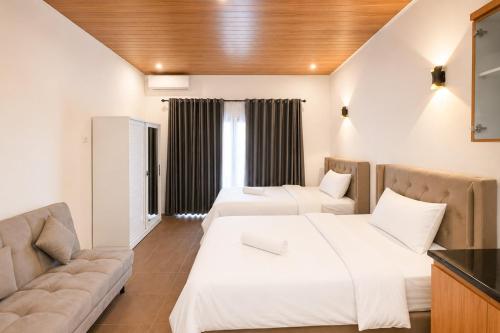 a hotel room with two beds and a couch at The Lavana Hotel Florida Kuta Mandalika in Kuta Lombok