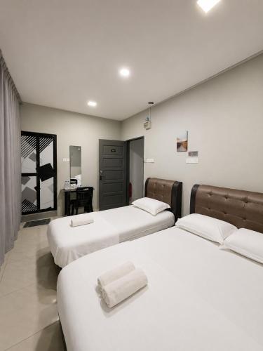 a bedroom with three beds with white sheets at Hotel Casaria in Paka
