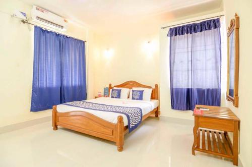 a bedroom with a bed and a window with blue curtains at Williams Beach Retreat in Colva