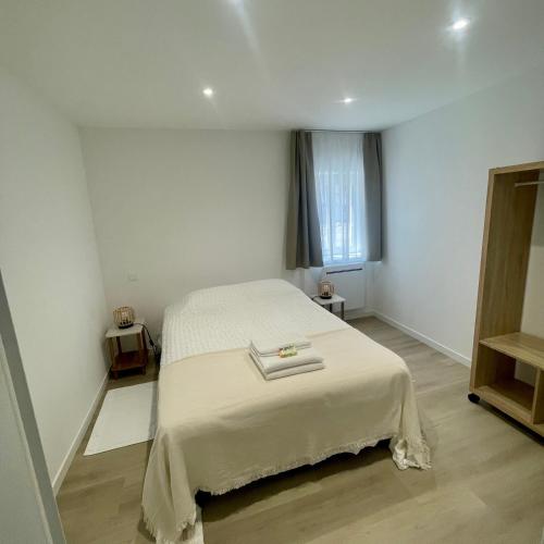a bedroom with a bed with a white blanket at La Maison Caroline in Surbourg