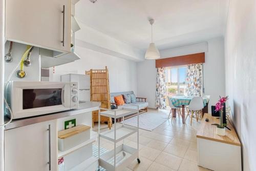 a kitchen and living room with a microwave and a table at Only 10 min from Lisbon city centre, 15 min driving from the beaches! in Almada