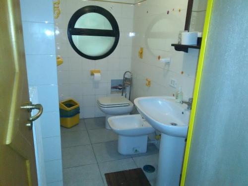bagno con lavandino, servizi igienici e specchio di B&B Il Tulipano a Taranto
