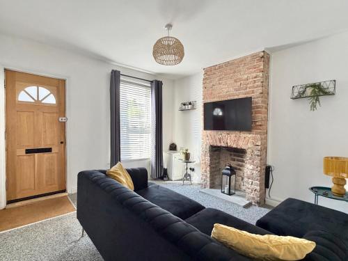 a living room with a black couch and a fireplace at Waterloo Street in King's Lynn