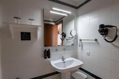 a white bathroom with a sink and a mirror at Hotel Tugasa Villa de Algar in Algar
