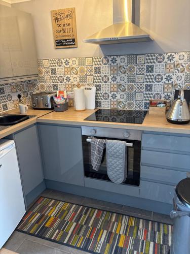a kitchen with blue cabinets and tiles on the wall at 78 Belle Aire in Hemsby