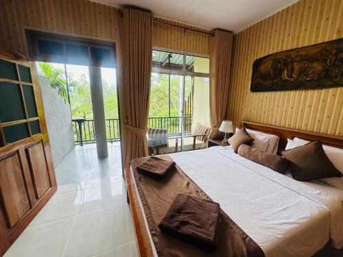 a bedroom with a large bed and a balcony at Liana Guest House Ella in Ella