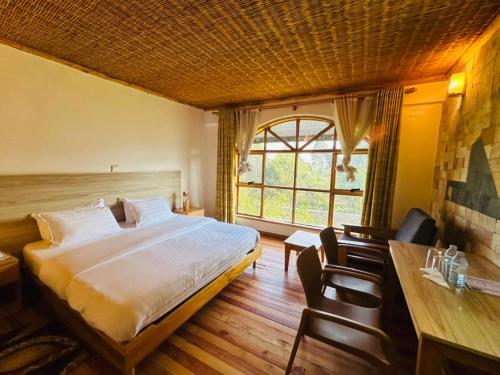 a bedroom with a bed and a table and chairs at Ikoro Hotel in Kisoro