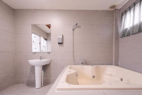a white bathroom with a tub and a sink at Guest Motel- Zhongli Branch in Pingzhen