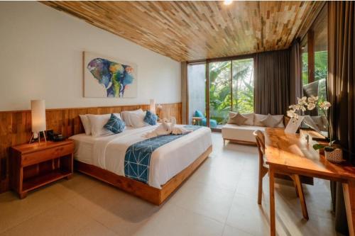 a bedroom with a bed and a table and a couch at Langit Pitu Villas in Ketewel