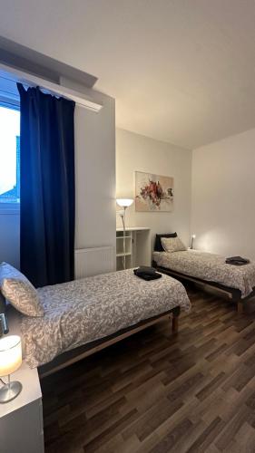 a bedroom with two beds and a blue curtain at B@Home Apartments in Sanem