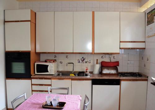 a kitchen with white cabinets and a table and a microwave at Gondolas Home Stay in Ragama
