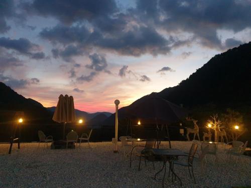 a sunset with a table and chairs and an umbrella at Danyang Euljeon 56 Pension in Danyang
