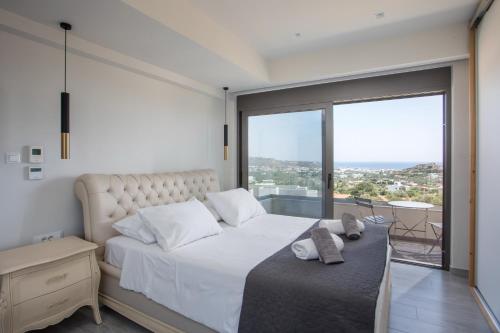 a bedroom with a white bed with a large window at Aetheria Luxury Villa in Kalithies