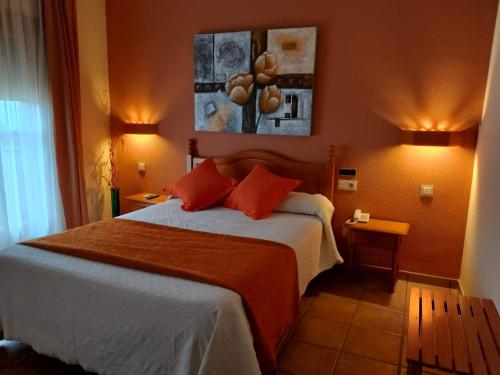 a hotel room with a bed with orange pillows at HOTEL RURAL HIDALGO in Torreperogil