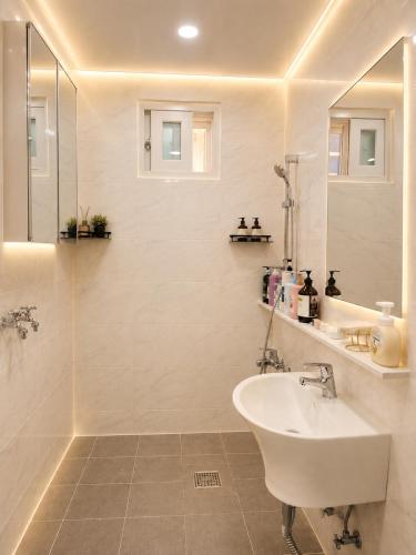 a white bathroom with a sink and a shower at SweetJian SweetStay in Suwon