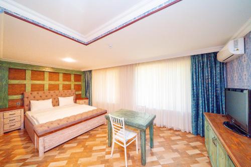 a bedroom with a bed and a table and a television at Quba Qala Resort in Quba