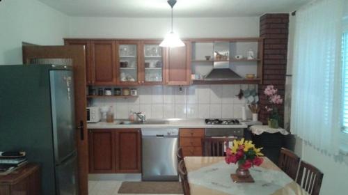 kuchnia z drewnianymi szafkami, stołem i lodówką w obiekcie Apartmani Vilma w Bibinje