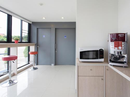 a kitchen with a microwave on a counter with two stools at HOP INN Buriram in Buriram