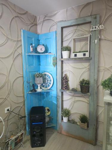 a room with a blue door and shelves with plants at Family Hotel Amor in Ruse