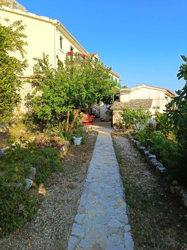 a garden with a stone path leading to a house at Holiday Home Alegra in Podgora