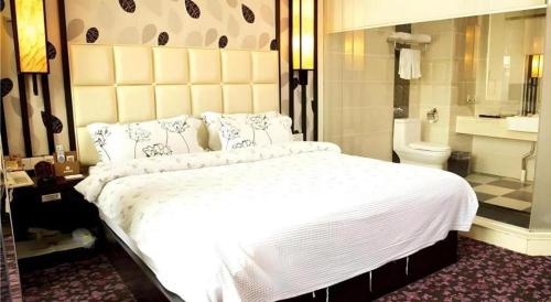 a bedroom with a large white bed and a bathroom at Behito Hotel in Dongguan
