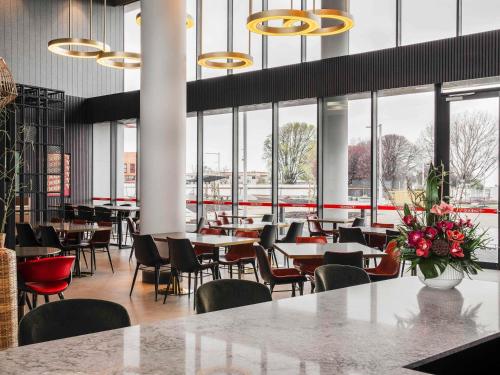 a restaurant with tables and chairs and windows at Novotel Devonport in Devonport
