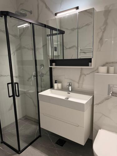 a white bathroom with a sink and a shower at Apartman PORTO in Trebinje