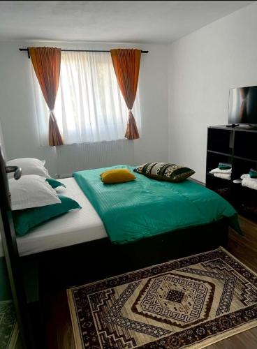 a bedroom with a bed with green sheets and a window at Gusturi din Livadă in Costeşti-Vîlsan