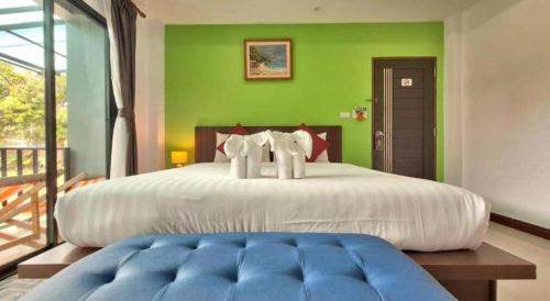 a bedroom with a large white bed with a green wall at Lantanoblesse in Ko Lanta