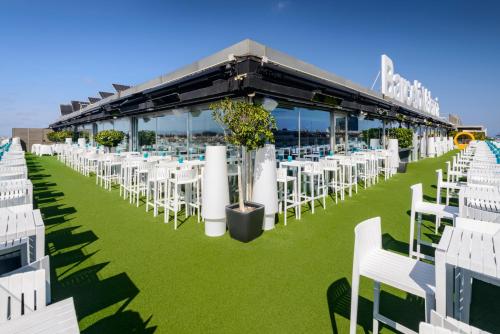 a row of white chairs and tables on the grass at Barceló Valencia in Valencia