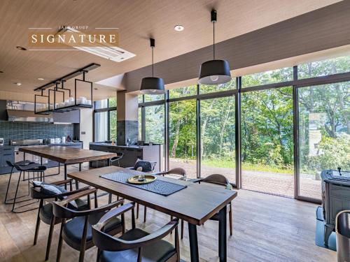 a dining room with tables and chairs and windows at SUKH Hakuba Chalet by Jade Villa in Hakuba
