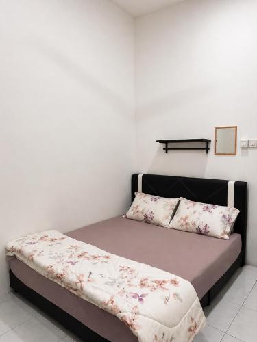 a small bedroom with a bed with flowers on it at Casaria Homestay Cherating in Kampong Baharu Cherating